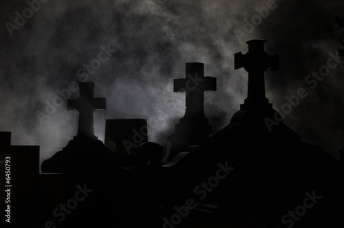 Headstone cross in Graveyard at night.