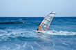 windsurfer sailing away form the beach on blue waters