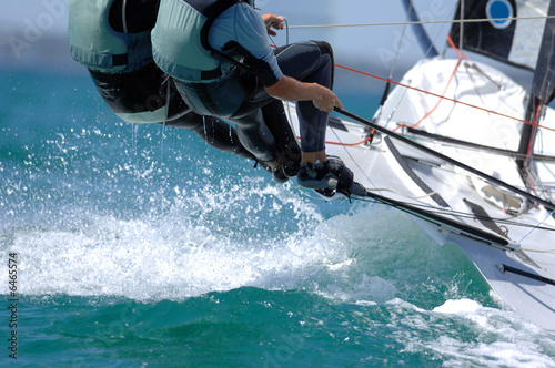 Photo: Sailors splash through the waves during a regatta. Sailors splash through the waves during a regatta.