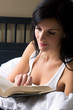 Young woman reading book in bed - detail