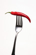 Red chili on fork on white