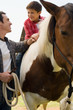 Father assisting son horseback riding
