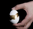 Single Hand Holding Gold Egg in White Shell Single Hand Holding Gold Egg in White Shell