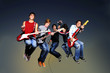 Young crazy group of musicians jumping with instruments