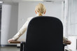 Rear view of a business woman sitting on a chair in an office.