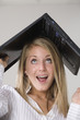A woman with a laptop over her head.