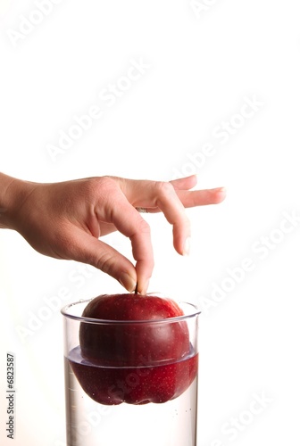 Photo: A hand dropping an apple in glass water A hand dropping an apple in glass water