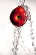 Water pouring  and splashing over a red delicious apple on white