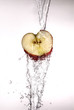 Apple with water pouring over it on white