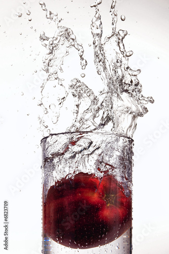 Photo: Apple splashing into a glass of water Apple splashing into a glass of water
