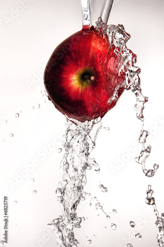 Photo: Water pouring and splashing over a red delicious apple on white Water pouring and splashing over a red delicious apple on white