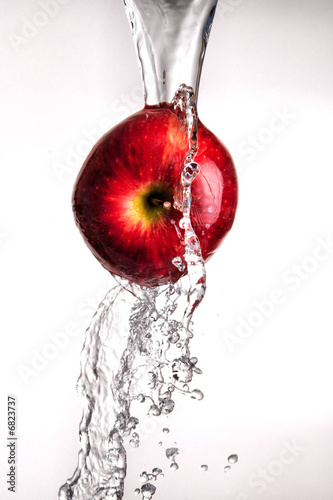 Photo: water pouring over apple on white water pouring over apple on white