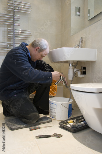Plumber at work in a modern bathroom