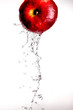 Water pouring  and splashing over a red delicious apple on white