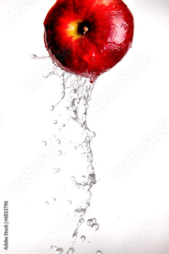 Photo: Water pouring and splashing over a red delicious apple on white Water pouring and splashing over a red delicious apple on white