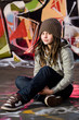 Young  girl sit  on a floorbefore the graffity background