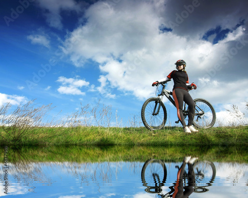 Foto: Young lady cycling near the lake Young lady cycling near the lake