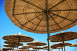 straw umbrellas on blue sky.