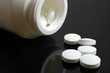 white pills and bottle on black background white pills and bottle on black background