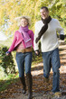 Couple running outdoors on path in park smiling