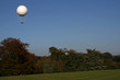 white hot air ballon in the air above the trees