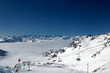 A ski lift and a ski slope sign, above the clouds.