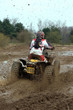 big yellow quad going through a deep mud