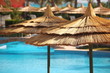 straw umbrellas on blue water.