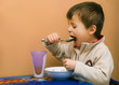 Toddler feeding himself at the table.