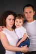 parents with child on hands on dark background