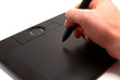 Photo: A human hand holding pen on graphic tablet for computer. A human hand holding pen on graphic tablet for computer.