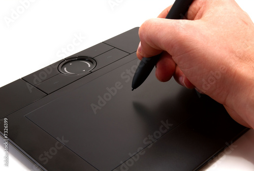 Photo: A human hand holding pen on graphic tablet for computer. A human hand holding pen on graphic tablet for computer.