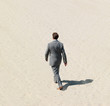 A business man walking in a desert with a clear shadow