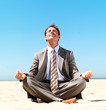 Business man doing yoga on the beach
