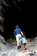 A father leading his son into a mysterious cave