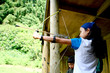 Young girl poised with bow and arrow, 