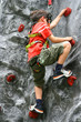 Young boy climbing up the indoor rockclimbing wall.