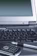Fragment of laptop with a mobile phone and a pen