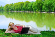 Beautiful young woman with laptop near the lake
