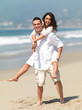 Young man giving piggyback to woman on beach