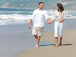 Couple holding hands on beach, walking.