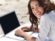 Smiling young woman using laptop on beach