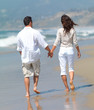 Walking on the beach, wan and woman holding hands.