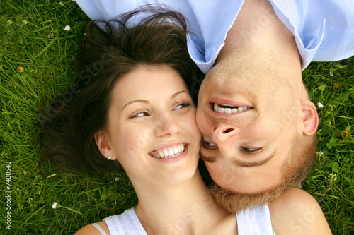Photo: young and happy couple is smiling on a meadow young and happy couple is smiling on a meadow