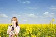 Young woman blowing her nose on the rape field