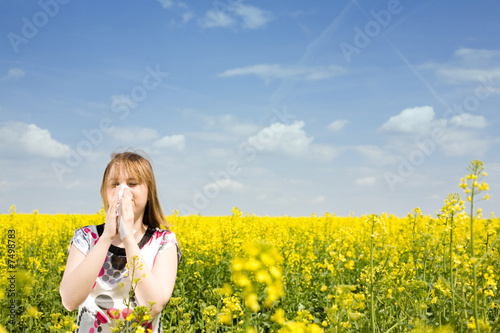Young woman blowing her nose on the rape field Young woman blowing her nose on the rape field
