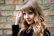 Blond woman on brick wall