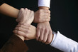 four hands holding tight together on black four hands holding tight together on black