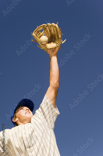 Photo: Baseball player catching ball in baseball glove, low angle view Baseball player catching ball in baseball glove, low angle view