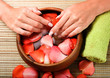 Hands in bowl of water with petals